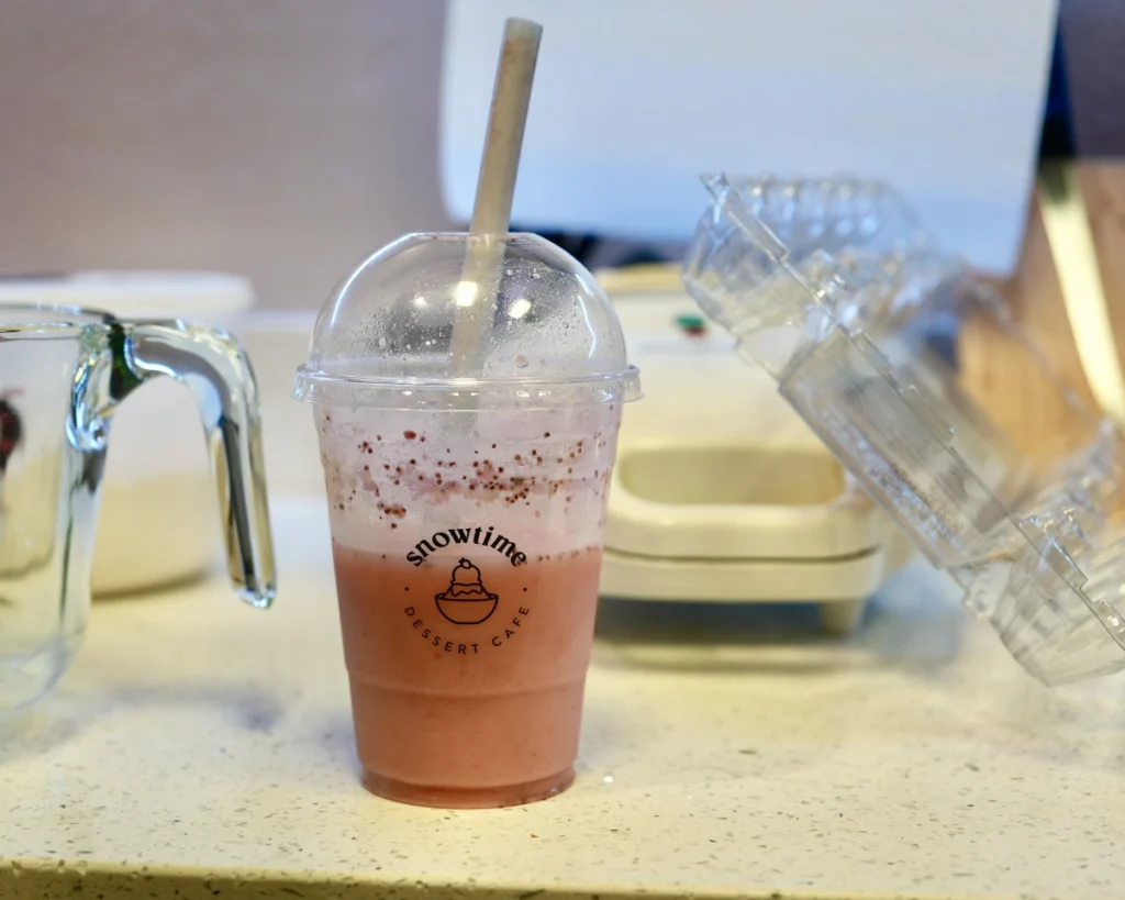 Half full to-go cup of strawberry almond milk from a bubble tea shop called Snow time